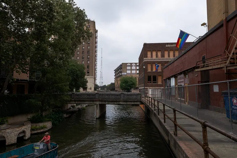 A photo of downtown San Antonio, overlooking the San Antonio river from a bridge and with another bridge and an American