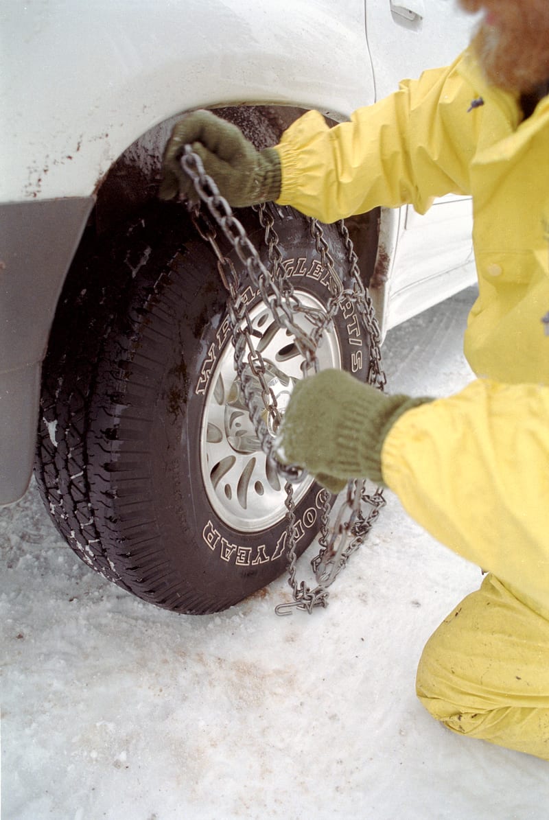 Snow chains fitted on a car tire on a snowy road in Oregon